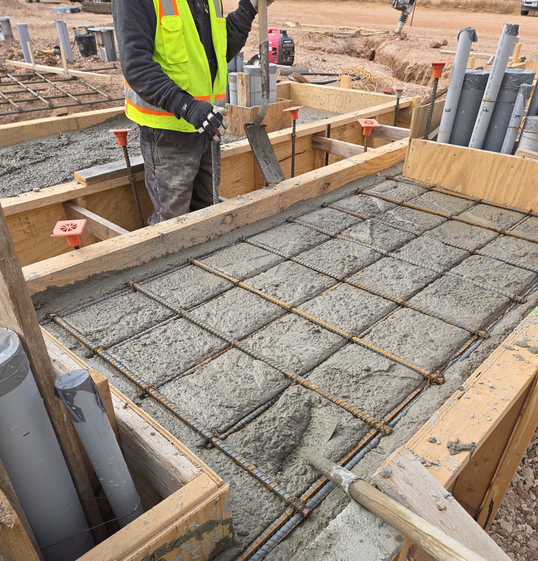 Reinforced foundation being poured in wooden forms over a rebar grid at a Levelland job site