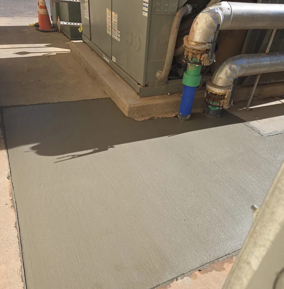 Fresh broom-finished slab poured around a commercial mechanical unit in Lubbock