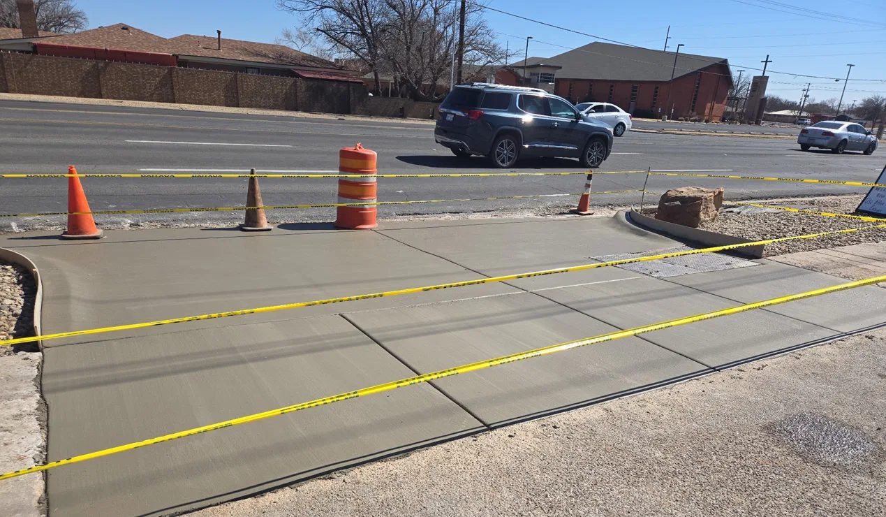 Freshly poured sidewalk with saw-cut joints in Lubbock, taped off while it cures